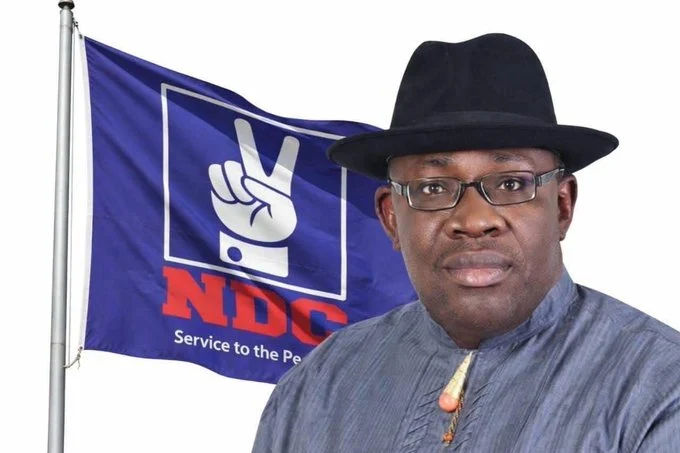 Seriake Dickson standing beside an NDC flag