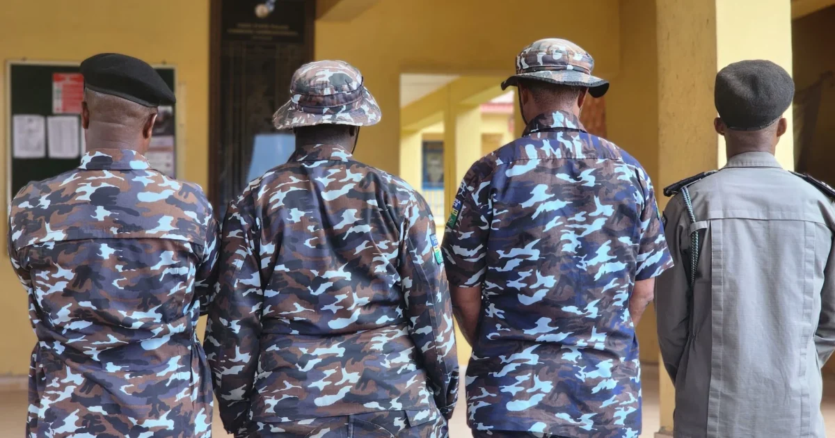 Four police officers arrested by the Ondo State Police Command stand with their backs to the camera
