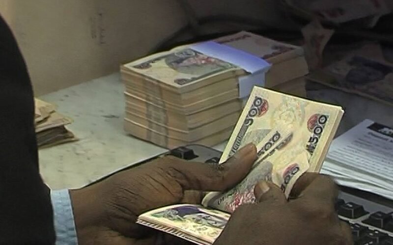 Nigerian naira notes being counted at a bank counter