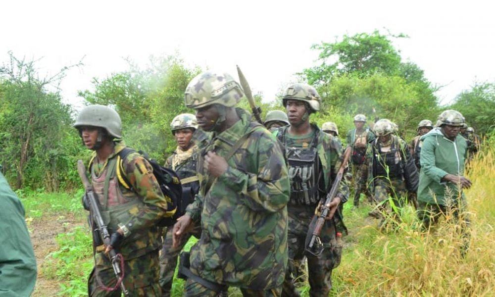 Nigerian soldiers moving through a rural area during a security operation