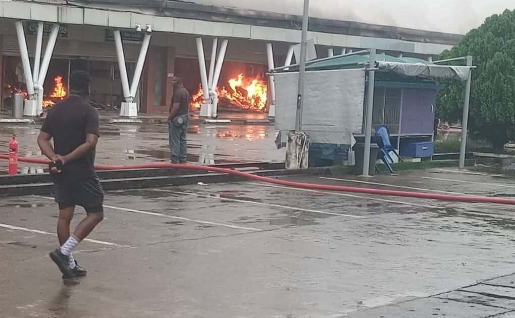Flames burn inside the SPAR shopping outlet in Calabar while responders work at the scene.