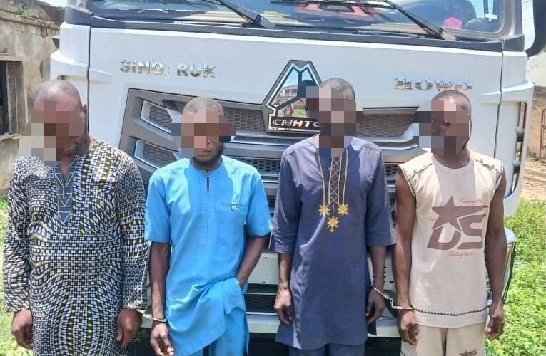 Four alleged truck hijacking suspects standing in front of a truck