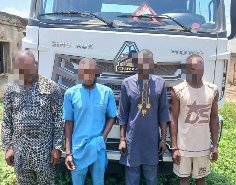 Four alleged truck hijacking suspects standing in front of a truck