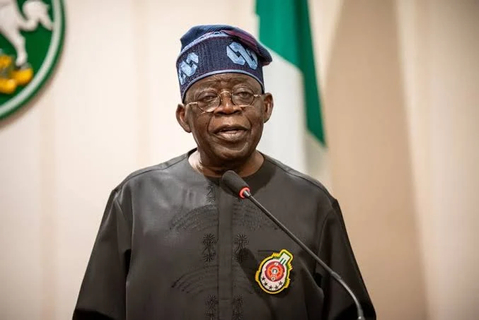 President Bola Tinubu speaking at a lectern with a Nigerian flag behind him