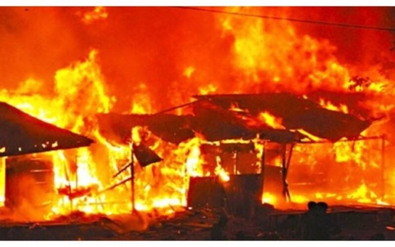 Fire burning through market structures at night.