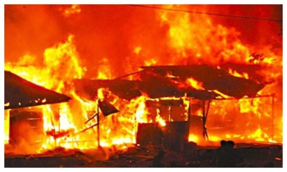 Fire burning through market structures at night.