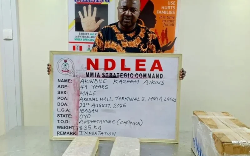 Akinbile Kazeem Aikins with NDLEA exhibit board and seized Captagon packages at MMIA Lagos