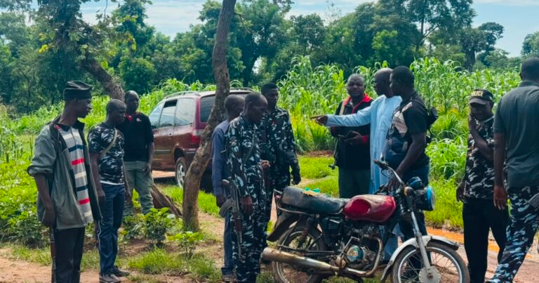 Police officers and local vigilantes beside a motorcycle after a Kaduna kidnap-rescue operation