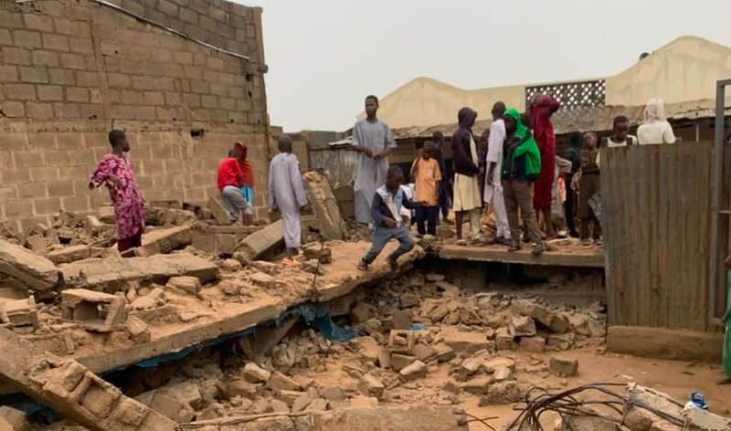 People stand near rubble after a collapsed Islamiyya school in Kano.