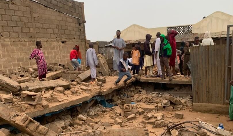 People stand near rubble after a collapsed Islamiyya school in Kano.