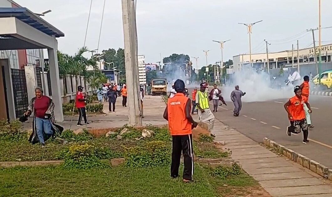 People running on a Kaduna road amid smoke during a political gathering