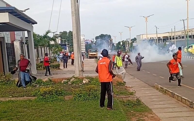 People running on a Kaduna road amid smoke during a political gathering