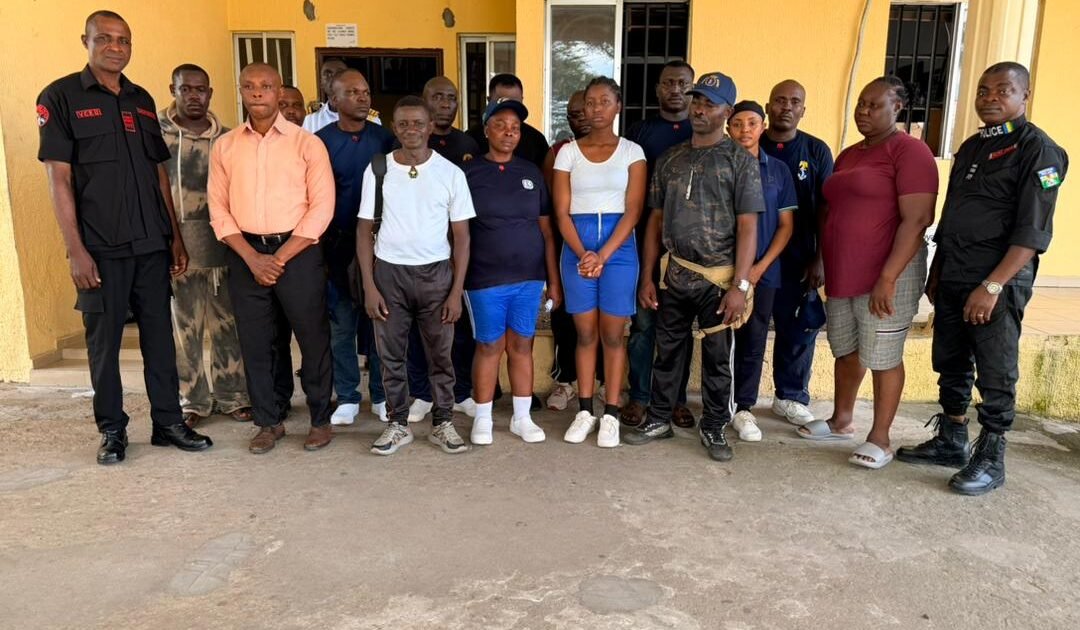 Security officials and suspected illegal recruitment trainees standing outside a building in Akwa Ibom