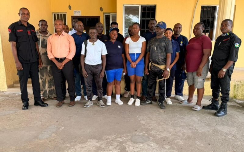 Security officials and suspected illegal recruitment trainees standing outside a building in Akwa Ibom