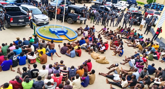 People seated in a police compound during an FCT Police raid screening in Abuja