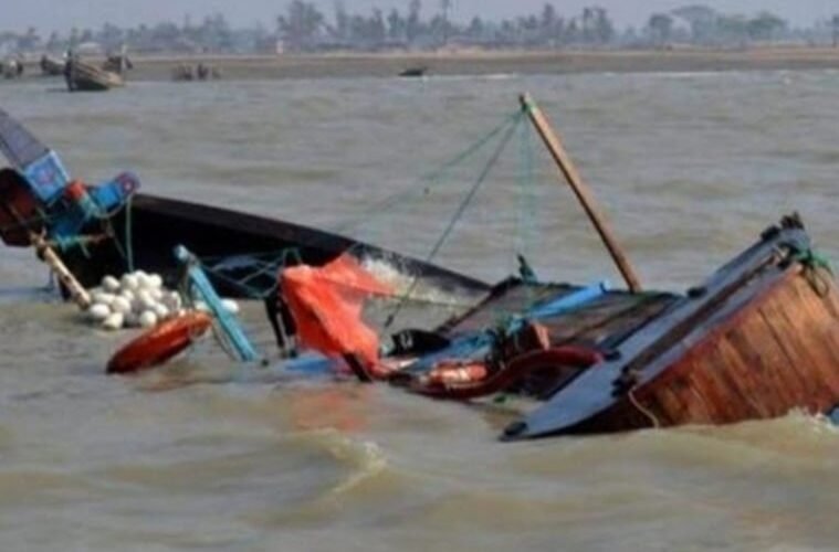 A capsized wooden boat partly submerged in muddy river water