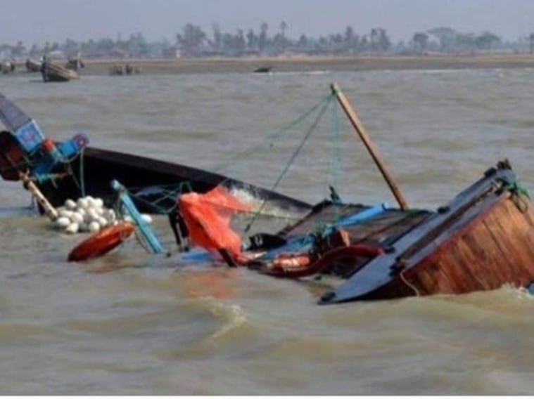 A capsized wooden boat partly submerged in muddy river water