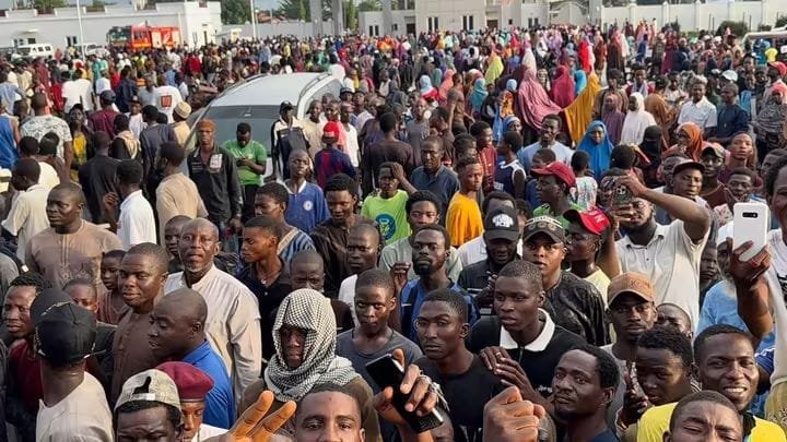 Large crowd gathered outside the Niger State Government House in Minna, with an ambulance visible