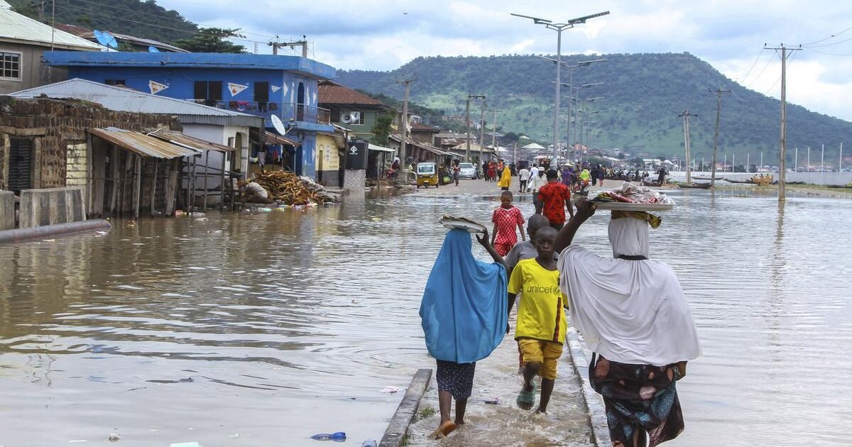 Residents wading through floodwater on a flooded Nigerian street during the NiHSA high flood-risk alert