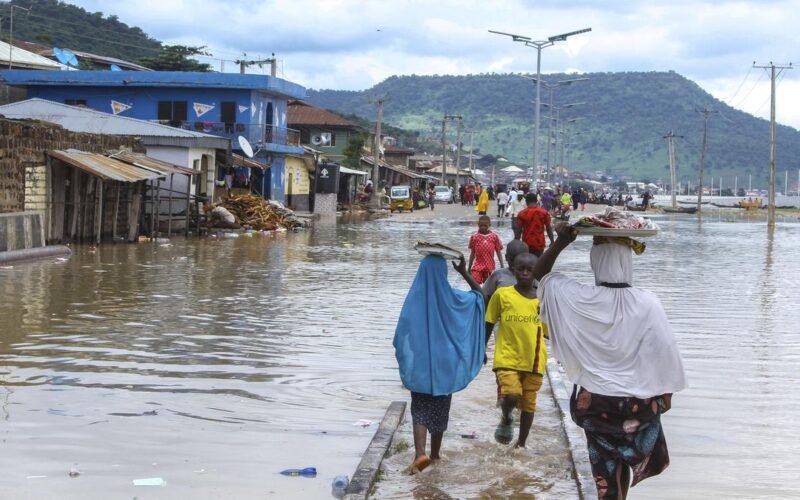 Residents wading through floodwater on a flooded Nigerian street during the NiHSA high flood-risk alert