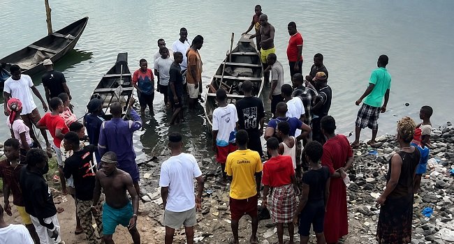 People gathered by boats at a riverside area in Okrika, Rivers State