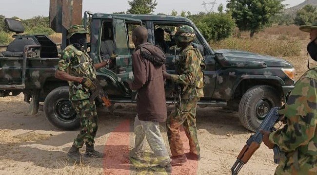 Troops stand near a military vehicle with a rescued kidnap victim
