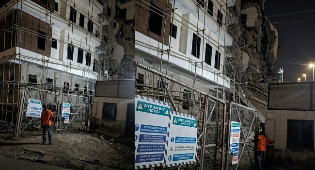 Building under construction with damaged sections and scaffolding at night