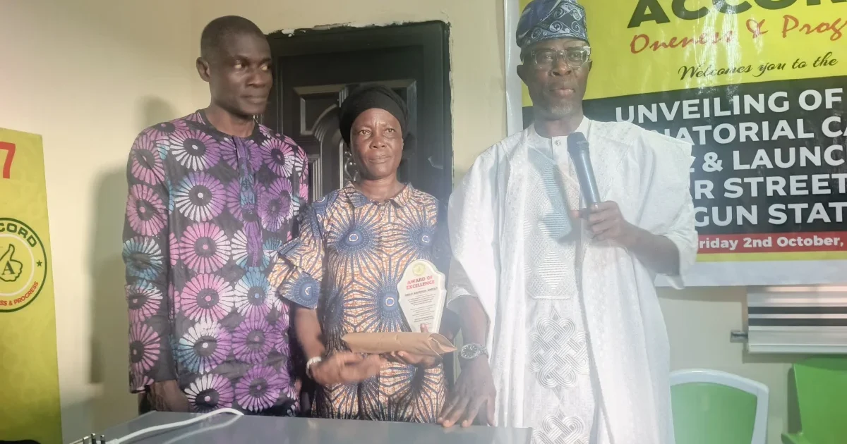 Three people standing with an award at the Accord event in Ogun