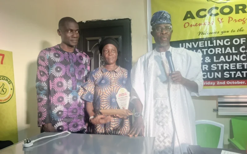 Three people standing with an award at the Accord event in Ogun