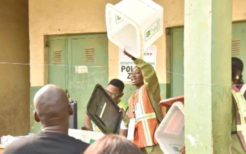 An election worker displaying an empty ballot box at a polling unit.