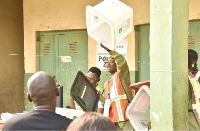 An election worker displaying an empty ballot box at a polling unit.