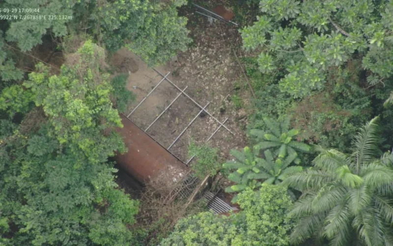 Aerial view of a rust-coloured cylindrical structure and metal framework surrounded by dense vegetation