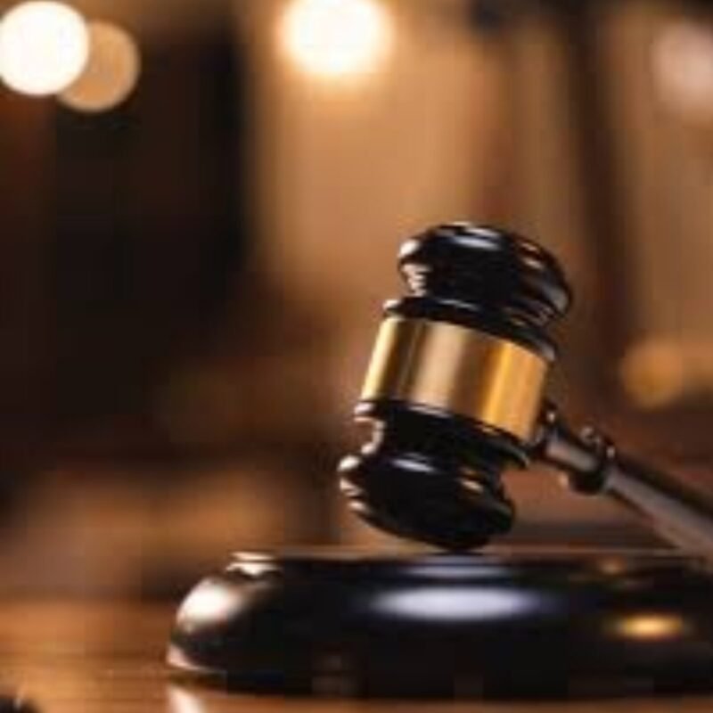 A judge's gavel on a wooden bench in a courtroom.