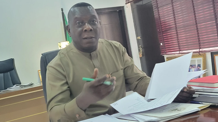 Stephen Odey seated at a desk holding documents