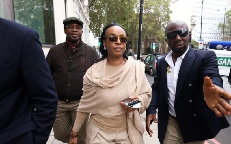 Diezani Alison-Madueke walking outdoors wearing sunglasses and beige clothing