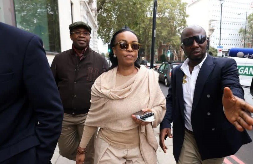 Diezani Alison-Madueke walking outdoors wearing sunglasses and beige clothing