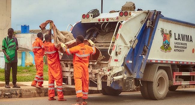 LAWMA workers loading refuse into a waste collection truck.