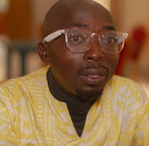 Journalist Lawrence Zongo wearing glasses and a yellow patterned shirt