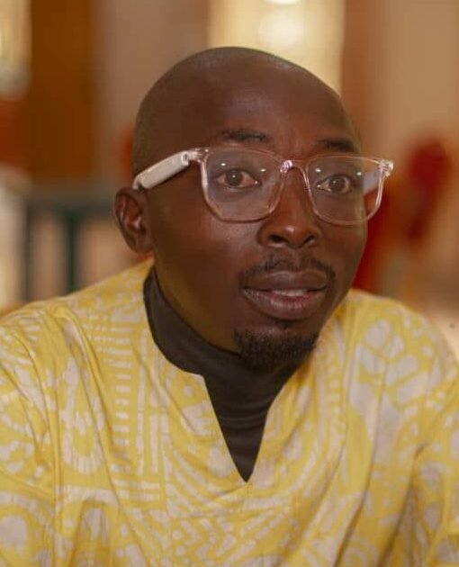 Journalist Lawrence Zongo wearing glasses and a yellow patterned shirt
