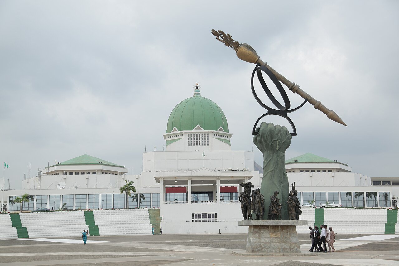 The National Assembly complex in Abuja seen across the forecourt, with the mace monument in the foreground.