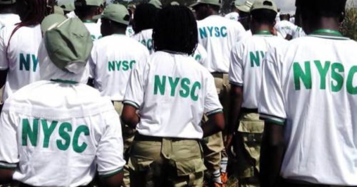 NYSC members wearing white shirts and green caps, seen from behind.