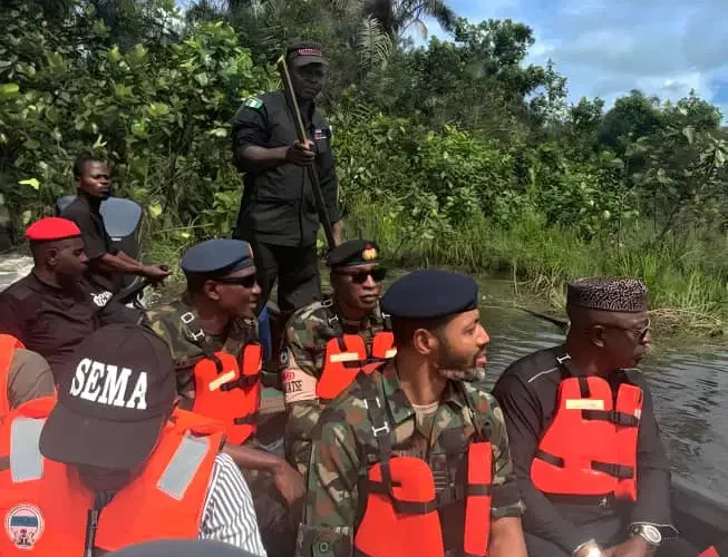 Military and emergency officials wearing life jackets on a boat during a site assessment.