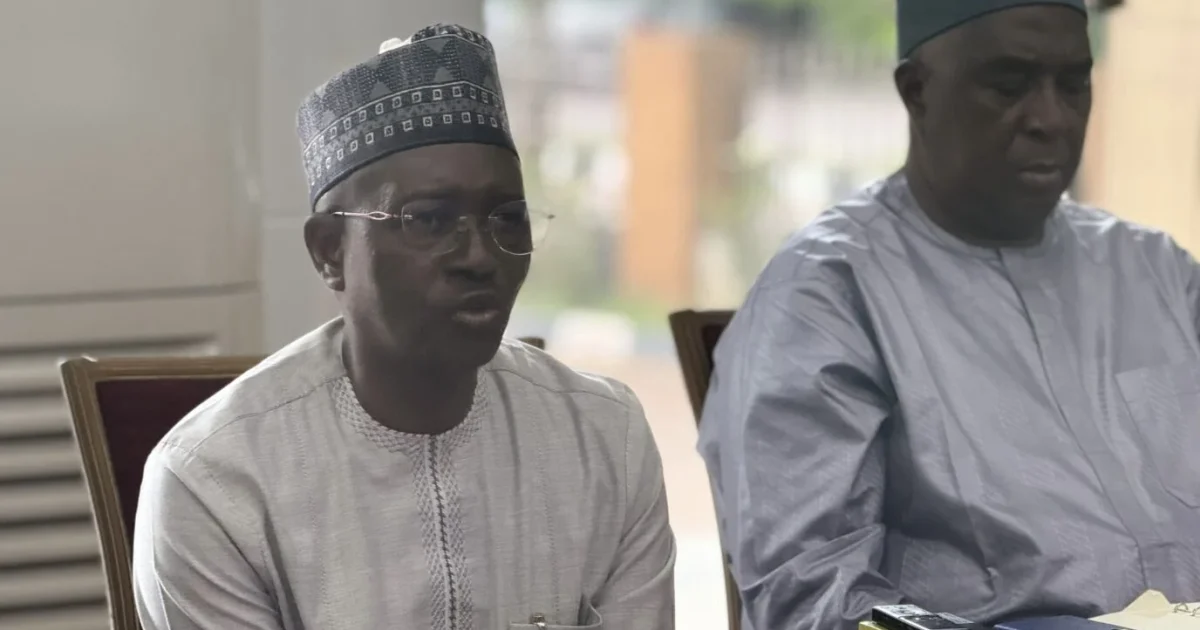 Jonathan Kure seated on the left and speaking at a press conference