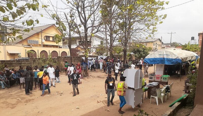 Voters queue at polling units with voting booths and election materials during the 2023 general elections.