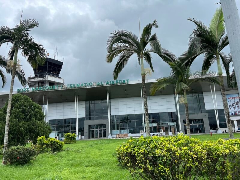Port Harcourt International Airport terminal entrance with the control tower behind palm trees.