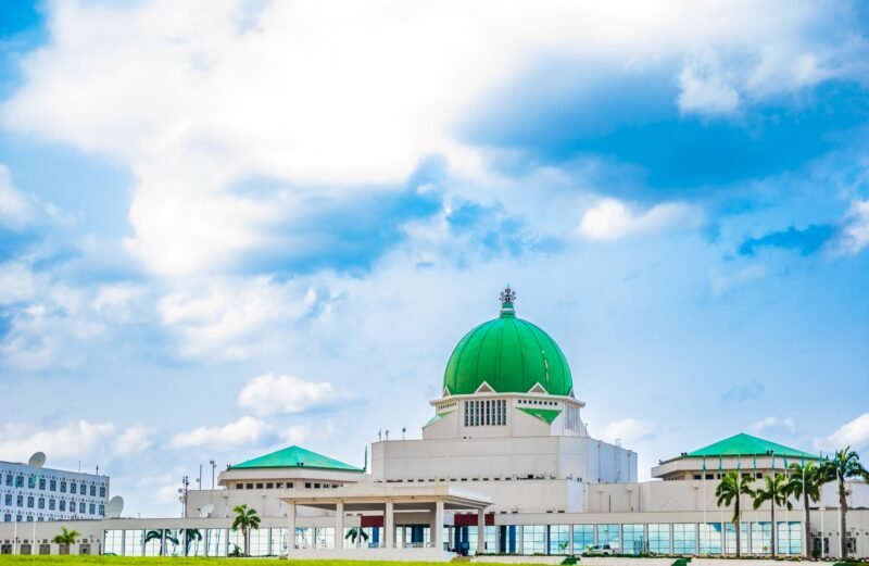 The green-domed National Assembly building stands beneath a cloudy sky in Abuja.