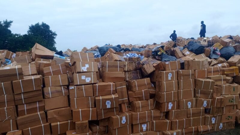 Mountains of confiscated packaged products stacked in the open ahead of a public destruction exercise.