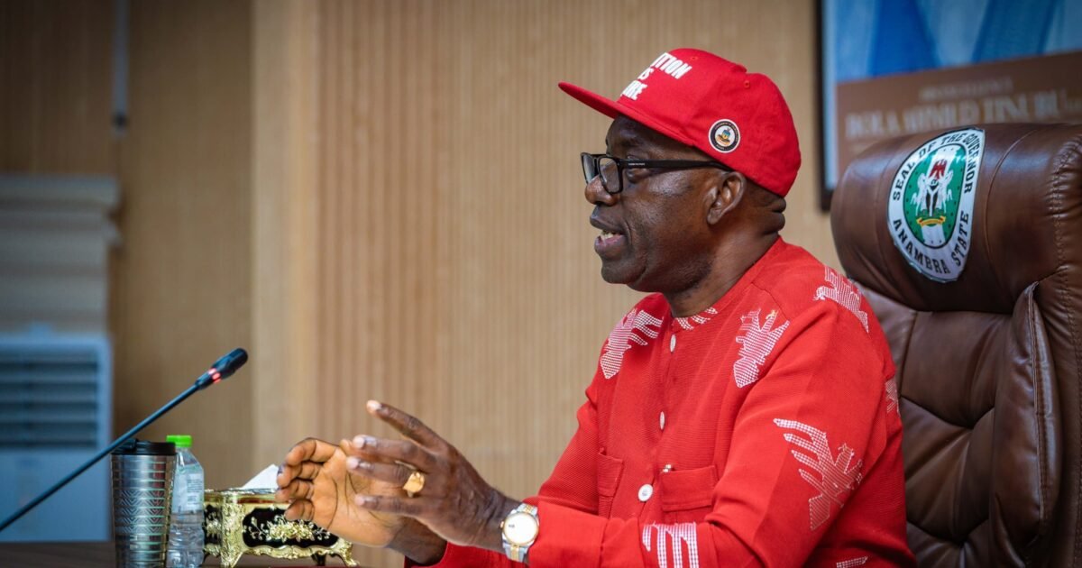 Anambra Governor Charles Soludo seated at a desk wearing a red cap and shirt